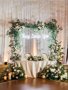 a table topped with flowers and candles under a neon sign