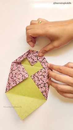 two hands are holding an origami piece