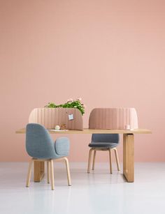 two chairs sitting at a table in front of a pink wall and potted plant