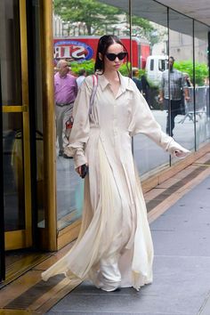 a woman walking down the street in a long dress