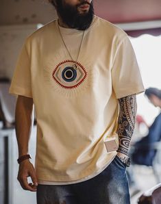 Looking to add some retro flair to your summer wardrobe? Meet the American Retro Guardian Eye Embroidered Cotton Men's T-Shirt! This casual tee is perfect for those laid-back summer days. Made from 100% cotton, it’s super soft and breathable, keeping you cool and comfortable no matter how hot it gets. The unique embroidered Guardian Eye design sets this t-shirt apart from the rest. It’s a great conversation starter and adds a touch of vintage style to your look. The beige color is versatile and easy to pair with anything in your closet. Whether you’re heading out for a day at the park or just lounging at home, this t-shirt has got you covered. The round neck and regular short sleeves provide a classic look that never goes out of style. With sizes from S to 2XL, finding the perfect fit is a Casual Summer T-shirt With Embroidered Graphics, Embroidered Streetwear T-shirt For Spring, Retro Cotton T-shirt For Summer, Embroidered T-shirt For Spring Streetwear, Retro Summer Cotton T-shirt, Spring Embroidered T-shirt For Streetwear, Casual Embroidered Graphic T-shirt For Summer, Embroidered Summer Tops For Streetwear, Retro Cotton T-shirt With Embroidered Graphics