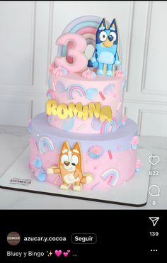 a pink cake decorated with cartoon characters and the number three on it's side