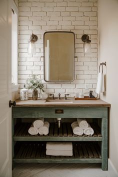 a bathroom with two sinks and towels on the rack in front of the sink is a brick wall