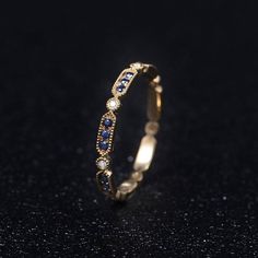 a gold ring with blue and white stones on the inside, sitting on a black surface