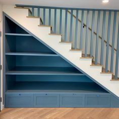 a blue book shelf under a stair case