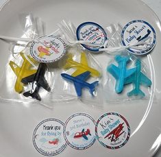 four small plastic airplane stickers on a white plate with clear cellophane wrappers