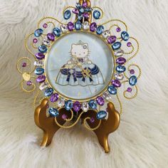 a hello kitty clock with purple, blue and gold beads on it's face