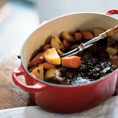 a red pot filled with stew and vegetables