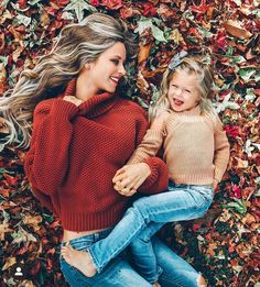 mother and daughter laying on the ground in autumn leaves