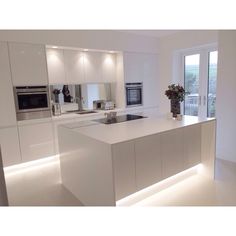 a modern kitchen with white cabinets and counter tops