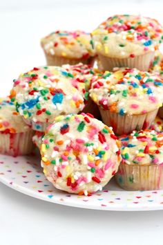 a white plate topped with lots of cupcakes covered in sprinkles