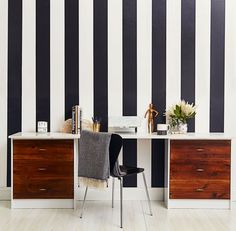 an office with black and white stripes on the wall, two desks are next to each other