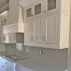 a kitchen with white cabinets and gray counter tops