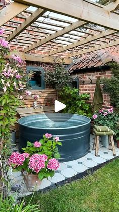 an outdoor hot tub in the middle of a garden with pink flowers and greenery