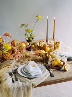 the table is set with plates, silverware and flowers in vases on it