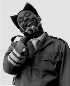 a black and white photo of a man in uniform talking on a cell phone while smiling