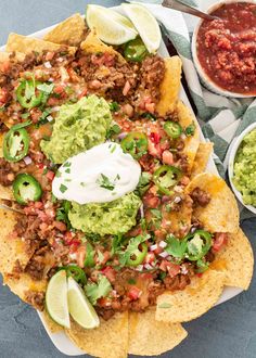 an overhead view of nachos with salsa and sour cream on the side, along with guacamole