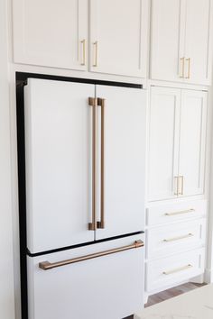 a white refrigerator freezer sitting inside of a kitchen next to wooden cabinets and drawers