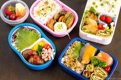 four bento boxes filled with different types of food and vegetables on top of a wooden table