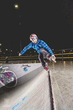 a man riding a skateboard down the side of a ramp at night with graffiti on it