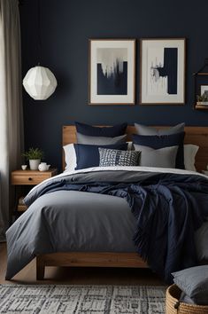 a bedroom with blue walls and grey bedding, two framed pictures on the wall