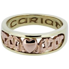 a gold ring with two hearts and the word caring on it's side, in front of a white background