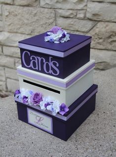 three stacked boxes with purple and white flowers on the top, one is for cards