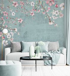 a living room with a couch, coffee table and flowers painted on the wall behind it