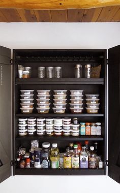 an open cabinet filled with lots of food and condiments on top of it