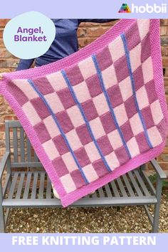 a pink and blue checkered blanket sitting on top of a bench next to a brick wall