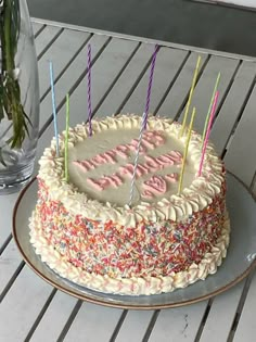 a birthday cake sitting on top of a table next to a vase filled with flowers