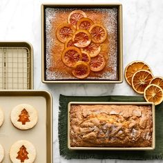 some oranges are sitting on trays next to bread and other food items that have been placed around them