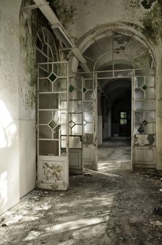 an old run down building with peeling paint on the walls and windows, in front of a doorway that leads to another room