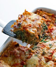 someone is taking a slice of lasagna casserole from the casserole dish