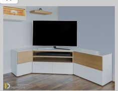 a flat screen tv sitting on top of a white cabinet in front of a wooden floor