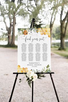 a sign with flowers and greenery on it that says, find your seat at the ceremony