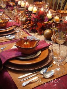 a table set for thanksgiving dinner with candles in the center and place settings on it