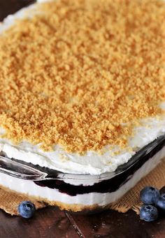 a close up of a cake on a table with blueberries and crumbs