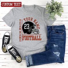 a t - shirt with the football helmet on it and some jeans next to it