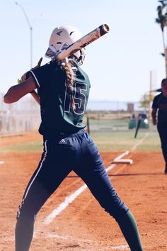 a woman holding a baseball bat on top of a field