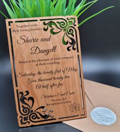 a wooden wedding card with an ornate design on the front and back, sitting next to a coin