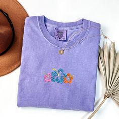 Hibiscus Flower Tshirt Aloha Hawaii Shirt Comfort Colors Women's Tshirts Oversized T-shirt Beach T Shirt Summer Tee PLEASE NOTE THAT THE PICTURES ON THE LISTING ARE SAMPLES ONLY. If interested in adding embroidery to the sleeve please go to this listing: https://www.etsy.com/listing/1674502020 Because it is made to order, we don't accept the return or exchange unless we make a mistake We are unable to replace or refund purchases based on the color and the font selections. Please make sure to be Relaxed Fit Crew Neck Top With Hibiscus Print, Casual Purple Tops With Embroidered Graphics, Embroidered Short Sleeve T-shirt For Beach, Embroidered Cotton T-shirt For Beach, Relaxed Fit Crew Neck T-shirt With Hibiscus Print, Embroidered Short Sleeve Beach T-shirt, Relaxed Fit Hibiscus Print Crew Neck T-shirt, Summer T-shirt With Hibiscus Print And Short Sleeves, Beach Embroidered Short Sleeve T-shirt