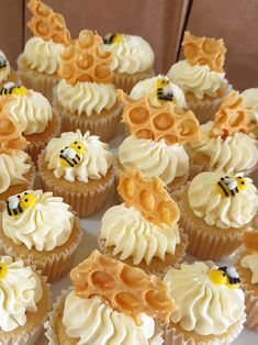 many cupcakes with white frosting and yellow decorations