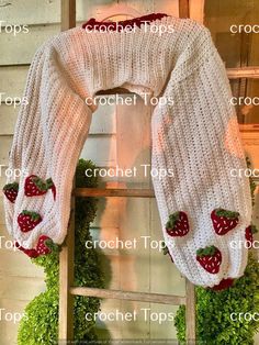 a knitted sweater with strawberries on it hanging from an old window sill