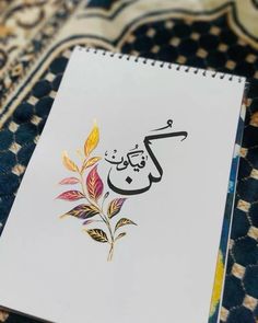 an arabic calligraphy is displayed on a notebook