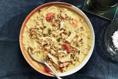 a bowl of chicken and rice soup with a spoon on the table next to it