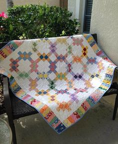 a quilt is hanging on a bench outside