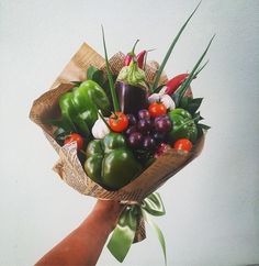 a hand holding a bouquet of fresh vegetables