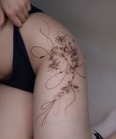 a woman's thigh with flowers on it and her arm behind her is shown