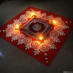 a red and white paper with candles in it on the floor next to a window